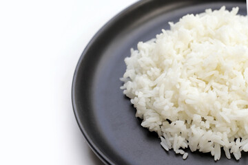 Cooked rice in black plate on dark background.