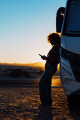 Woman in silhouette against sunset beautiful light. Travel people with camper camping car van for...