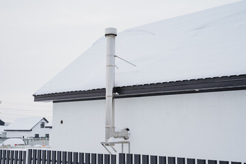 A metal chimney pipe made of stainless steel, a hood for heating is mounted on the wall of a...