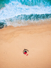 Vertical view of summer beach holiday vacation concept with blue waves ocean and couple of tourists walking and enjoying on the sand alone - concept of travel and freedom happiness leisure outdoor