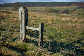 January midday and the bright sun highlight this lone gatepost and wooden style  Breary Banks. Masham, North Yorkshire. UK