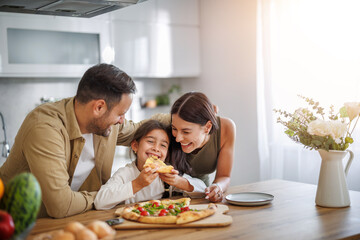 Mom, dad and daughter are eating pizza at home