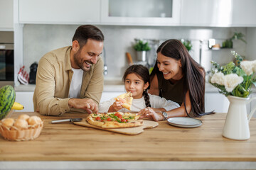 Mom, dad and daughter are eating pizza at home