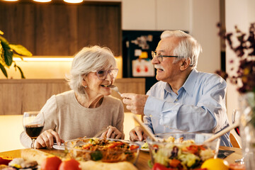 A senior couple is sharing food at home.