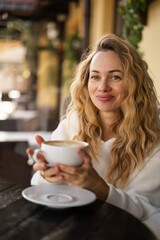 Happy young woman enjoying a cup of coffee in a cafe. Lunch break. Portrait of happy customer in coffee shop drinking her morning caffeine or cappuccino