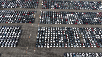 Obraz na płótnie Canvas Aerial view of a new car lot, neatly arranged vehicles reflecting uniformity and precision, symbolizing organized commerce and transportation.