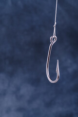 Large fishing hook on blue background with space for text