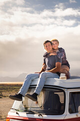 Fototapeta na wymiar Young love couple sit down on a roof van enjoy travel lifestyle and holiday vacation together - concept of van life and free alternative trip with pretty couple enjoying outdoor and hug