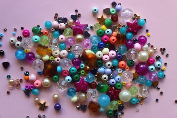 Various colorful beads on bright pink background. Top view.
