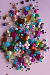 Various colorful beads on bright pink background. Top view.