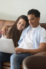 Young couple moving to a new home relaxing sitting on the sofa using computer laptop, smiling happy for moving to new apartment