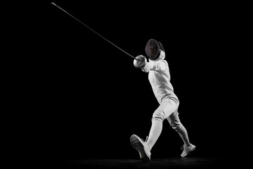 Dynamic portrait of female fencer training attack technique in motion. Swordswoman focused and...