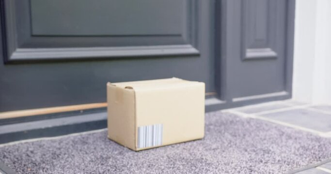 Delivery in cardboard box on ground outside front door, slow motion