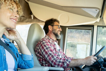 Man driving camper smiles while driving with his wife company. Concept of travel, vacation and life together