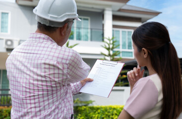 Senior home inspector explains Inspection results with homeowner, handyman holding clipboard and...