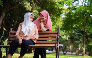 Fototapeta premium Muslim careful caregiver or nurse taking care of the patient in the hospital park. Happy Muslim mother in hijab hugging daughter. Concept of Savings and Senior Health Insurance, a Happy Family