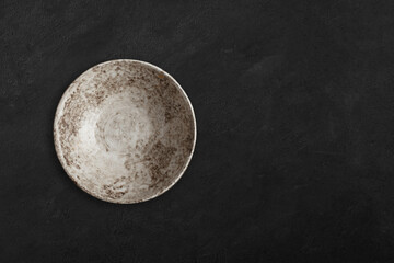 Handmade empty ceramic plate top view with copy space on dark concrete table. Minimalism. Eco...