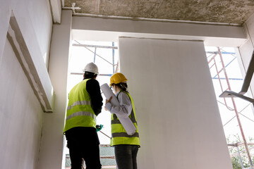 Engineers and Architect Caucasian looking at blueprint of building construction, planning the work in a professional. inspector is looking at steel structure and materials at construction site.