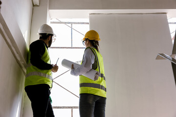 Engineers and Architect Caucasian looking at blueprint of building construction, planning the work in a professional. inspector is looking at steel structure and materials at construction site.