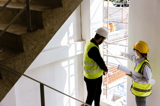 Engineers and Architect Caucasian looking at blueprint of building construction, planning the work in a professional. inspector is looking at steel structure and materials at construction site.