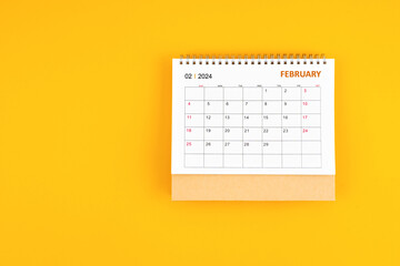 February 2024 desk calendar on yellow color background, position with copy space.