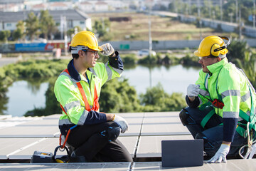 Professional electric engineers survey and inspect solar panels installation on the factory metal sheet roof top.