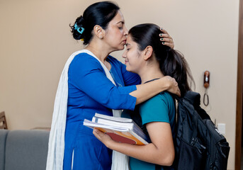 Indian mother Wishing her daughter best wishes for exam by kissing her on forehead and hug her