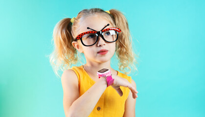 Technology for children: a girl wearing funny glasses uses a smartwatch. Portrait.
