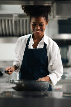 Happy African American woman standing with arms crossed while working as chef in a restaurant. Cooking class. culinary classroom. happy young african woman students cooking in cooking school.