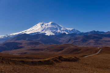 Landscape of Mount Elbrus, snow-capped peak against blue sky background