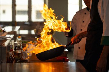 Thai Asian man professional chef cooking meal with fire at kitchen restaurant. culinary classroom....