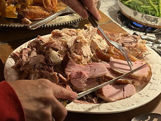 Cut pieces of roasted turkey and ham on a serving platter
