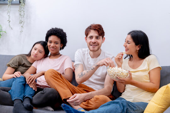 Group of friends sharing popcorn and enjoying leisure time together on a sofa.  - Powered by Adobe