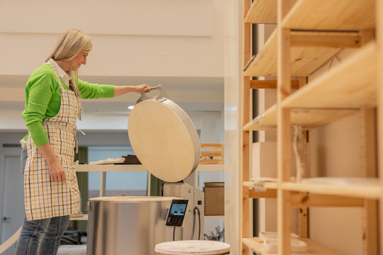entrepreneurial senior woman opening ceramic kiln for new orders - Powered by Adobe