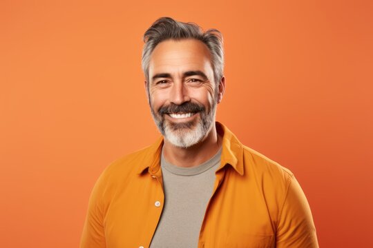 Portrait of handsome mature man in orange shirt on orange background.