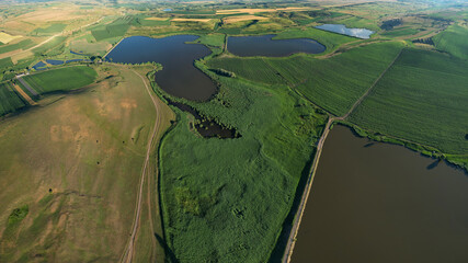 Aerial drone view above a natural reservation consisting of several lakes, ponds and swamp areas in...