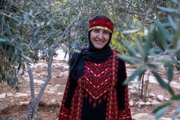 Portrait Of woman wearing palestinian traditional clothes in olive trees field holding branch in her hand