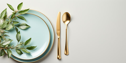 Golden cutlery arranged neatly on a white plate with a blue rim, adorned with green leaves - obrazy, fototapety, plakaty