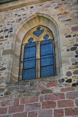 Fenêtré ancienne avec son entourage de pierre en forme d'ogive et ses carreaux en vitrail décorés sur une riche maison ancienne dans le petit village de Manglieu dans le puy de dôme