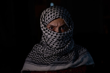 portrait of pearson wearing white keffiyeh on dark background with anger expression on his eyes 