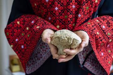A Palestinian woman holds a stone in her hands, which represents the only weapon to resist the...