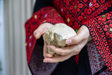 A Palestinian woman holds a stone in her hands, which represents the only weapon to resist the...