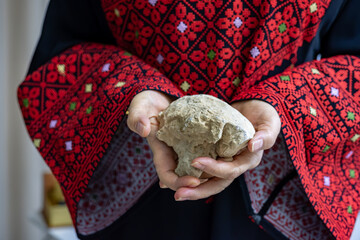 A Palestinian woman holds a stone in her hands, which represents the only weapon to resist the...