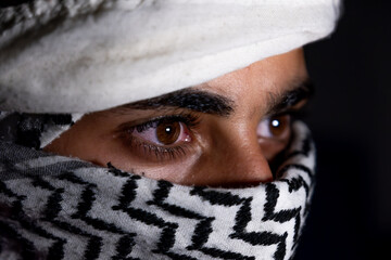 portrait of pearson wearing white keffiyeh on dark background with anger expression on his eyes due...