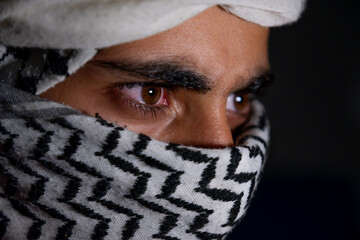 portrait of pearson wearing white keffiyeh on dark background with anger expression on his eyes due...