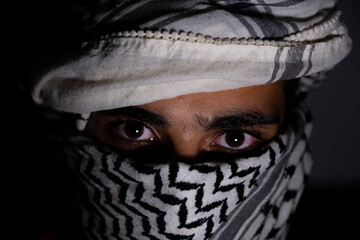 portrait of pearson wearing white keffiyeh on dark background with anger expression on his eyes due...