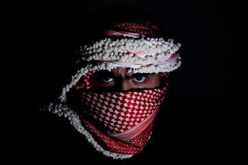 portrait of pearson wearing red keffiyeh on dark background with anger expression on his eyes due...