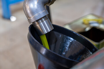 Filling fresh olive oil using a funnel and weighing scale in a pressing factory