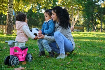 Dominican mother easing sibling rivalry teaching her kids to share the soccer ball.