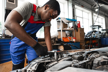 Young African male mechanic repairs car in garage close up